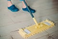 Woman cleaning floor with yellow mop at home. Microfiber mop isolated on white wooden floor background, closeup, indoors Royalty Free Stock Photo