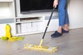 Woman cleaning floor with yellow mop at home. Microfiber mop  on white wooden floor background, closeup, indoors Royalty Free Stock Photo