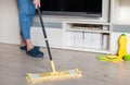 Woman cleaning floor with yellow mop at home. Microfiber mop  on white wooden floor background, closeup, indoors Royalty Free Stock Photo