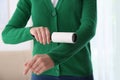 Woman cleaning green jacket with lint roller, closeup