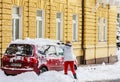 Woman cleaning her car from snow and frost on a winter morning.