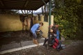 Woman cleaning her riding boots with her brown horse in the background Royalty Free Stock Photo