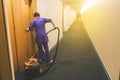 Woman is cleaning the hotel room. Hotel cleaning services. Working as a maid at the hotel. Long hotel corridor with