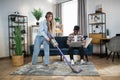 Woman cleaning house while man working on laptop Royalty Free Stock Photo