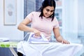 Woman, cleaning and iron clothes in house with smile for tidy with dirty laundry in living room with outfit. Ironing Royalty Free Stock Photo