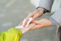Woman cleaning kid hands with antiseptic tissue outdoors. Hands hygiene. Female using a antibacterial wet napkin wipe Royalty Free Stock Photo