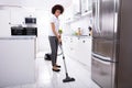 Woman Cleaning Kitchen Floor With Vacuum Cleaner Royalty Free Stock Photo