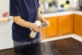 Woman cleaning kitchen table surface with disinfectant spray bottle. Royalty Free Stock Photo