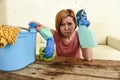 Woman cleaning living room table with cloth and spray bottle tired in stress