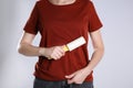 Woman cleaning red t-shirt with lint roller on background, closeup Royalty Free Stock Photo