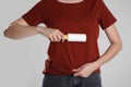 Woman cleaning red t-shirt with lint roller on grey background Royalty Free Stock Photo