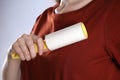 Woman cleaning red t-shirt with lint roller on background, closeup Royalty Free Stock Photo