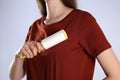 Woman cleaning red t-shirt with lint roller on grey background, closeup Royalty Free Stock Photo