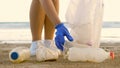 Woman cleaning sandy beach from plastic on seashore. Volunteer collect garbage in a trash bag. Ocean plastic pollution Royalty Free Stock Photo