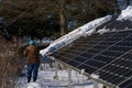 Woman cleaning snow covered solar panels on a bright and cold winterÃ¢â¬â¢s day.