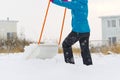 Woman cleaning snow with shovel in winter day. Woman shovelling snow walkway in front of house