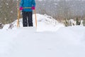 Woman cleaning snow with shovel in winter day. Woman shovelling snow walkway in front of house