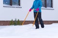 Woman cleaning snow with shovel in winter day. Woman shovelling snow walkway in front of house