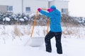 Woman cleaning snow with shovel in winter day. Woman shovelling snow walkway in front of house