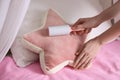 Woman cleaning star shaped cushion with lint roller at home, closeup
