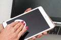 Woman cleaning tablet device with cotton paper tissue, wiping black screen, closeup detail. Blurred laptop keyboard background Royalty Free Stock Photo