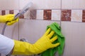 Woman cleaning tiles in bathroom