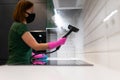 Woman cleaning tiles in the kitchen with steam machine. Royalty Free Stock Photo