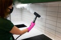 Woman cleaning tiles in the kitchen with steam machine. Royalty Free Stock Photo