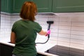 Woman cleaning tiles in the kitchen with steam machine. Royalty Free Stock Photo