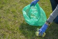 Woman cleaning up nature of garbage. Volunteer hands with blue gloves picking up trash into plastic bag. Volunteering