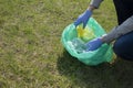 Woman cleaning up nature of garbage. Volunteer hands with blue gloves picking up trash into plastic bag. Volunteering