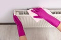 Woman cleaning white radiator with rag indoors, above view Royalty Free Stock Photo