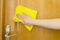 Cleaning wooden door with a yellow cloth