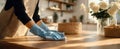 The woman cleaning a wooden table with gloves in a bright kitchen setting. AI generated image Royalty Free Stock Photo