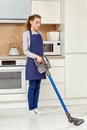 A woman cleans the floor with a cleaning vacuum cleaner in a modern kitchen. Royalty Free Stock Photo