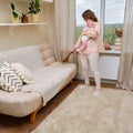 Woman cleans the home living room with an infant baby in her arms Royalty Free Stock Photo