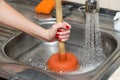Woman cleans plunger with clogged sink Royalty Free Stock Photo