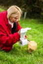 A woman cleans up dog poop on the lawn in the yard of the house. Close-up. Roll of toilet paper and excrement on the grass.