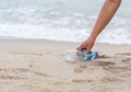 Woman cleans up by picking up plastic bottles at the beach. Concept of protecting the environment, saving the world, recycling,