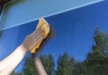 A woman cleans a window with a rag and water in the street.