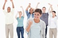 Woman clenching her fist with people behind raising their arms Royalty Free Stock Photo