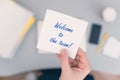 Woman clerk sitting holding note paper sticker with welcome to the team phrase. Business concept. Royalty Free Stock Photo