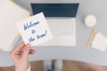 Woman clerk sitting holding note paper sticker with welcome to the team phrase. Business concept.