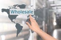 Woman clicking Wholesale button and world map with blurred view of warehouse
