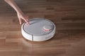 Woman clicks start button of robot vacuum cleaner. Modern smart electronic concept of household technology