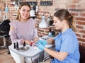 Woman client choosing color of nail polish, talking with manicurist