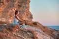 Woman on cliff enjoying landscape and writing in notebook. Contemplation nature and keeping diary concept, copy space