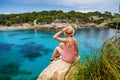 A woman on a cliff, enjoying view of Cala Gat beach in Mallorca