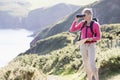 Woman on cliffside path using binoculars