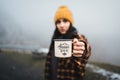 Woman climber holding outdoor coffee mug with popular adventure begins text